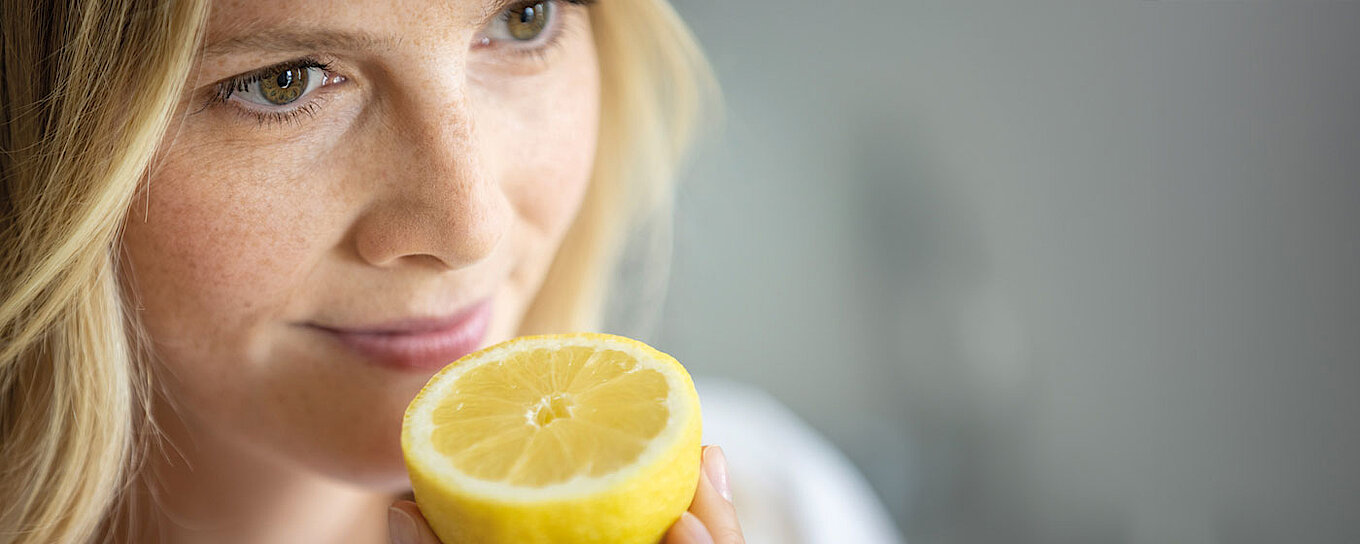 Eine Frau riecht an einer Zitrone, denn unser Bereich Aromen bietet ein Produktportfolio an maßgeschneiderte Aromen