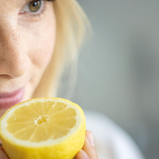 A woman smells a lemon, because we offer a product portfolio of customised flavors