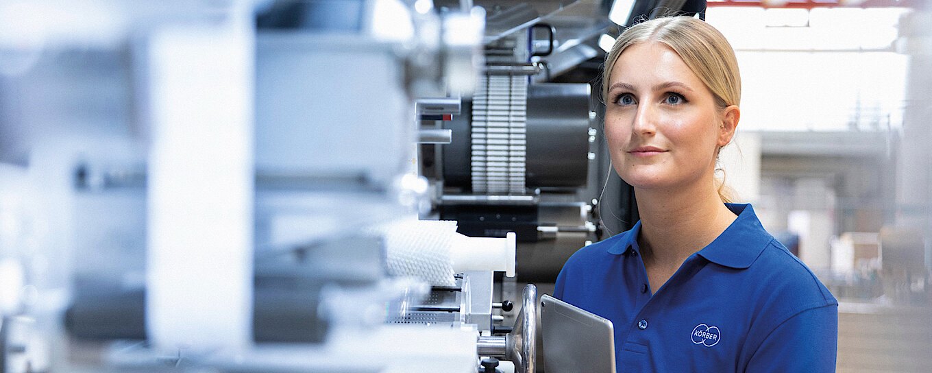 A Körber employee stands at a machine from Körber Technologies.