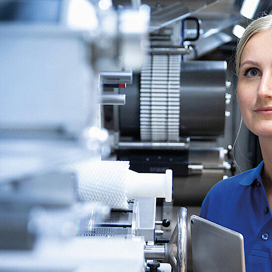 A Körber employee stands at a machine from Körber Technologies.